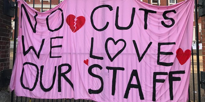 Image shows a large pink banner with the words “No cuts, we love our staff”